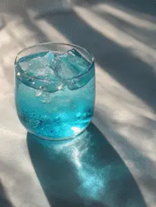 Blue salt trick drink in a glass with ice cubes and shimmering blue color.
