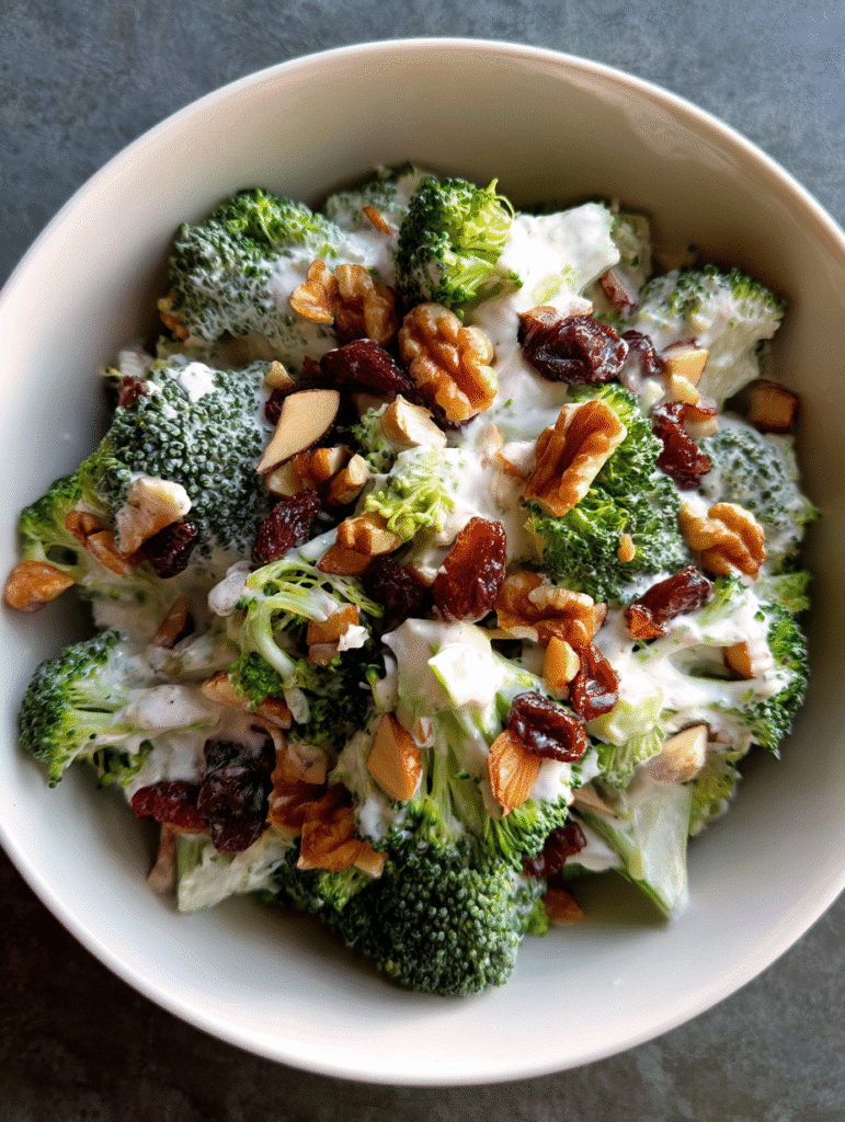 Broccoli salad recipe with creamy dressing, walnuts, almonds, and dried cranberries.
