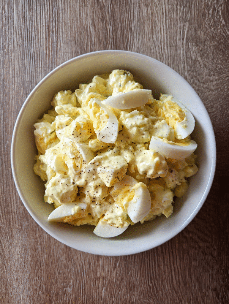 Egg Salad Recipe Egg salad recipe with chopped eggs, creamy mayonnaise dressing, and black pepper in a white bowl.