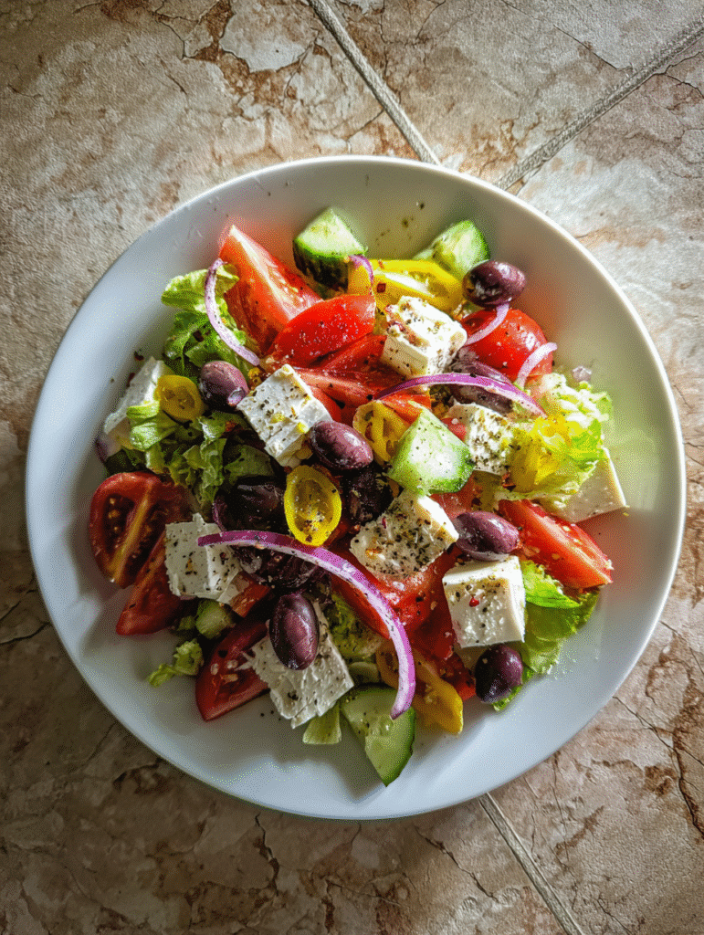 Greek Salad Recipe Greek salad with feta cheese, tomatoes, cucumbers, olives, and red onions on a white plate.
